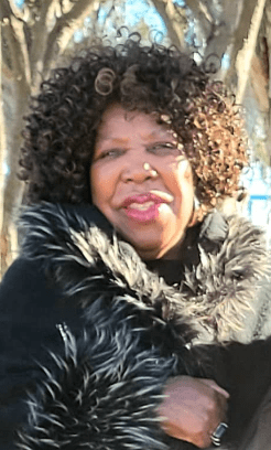 A woman with curly hair wearing a black coat and fur.