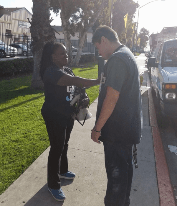 A woman standing next to a man on the sidewalk.