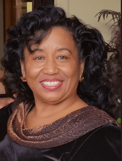 A woman with curly hair and a brown scarf.